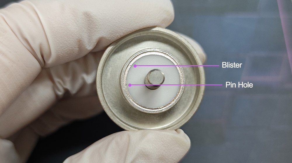 Hermetic seal failure analysis showing blister and pinhole defects in the nickel plating layer of a brazed ceramic component
